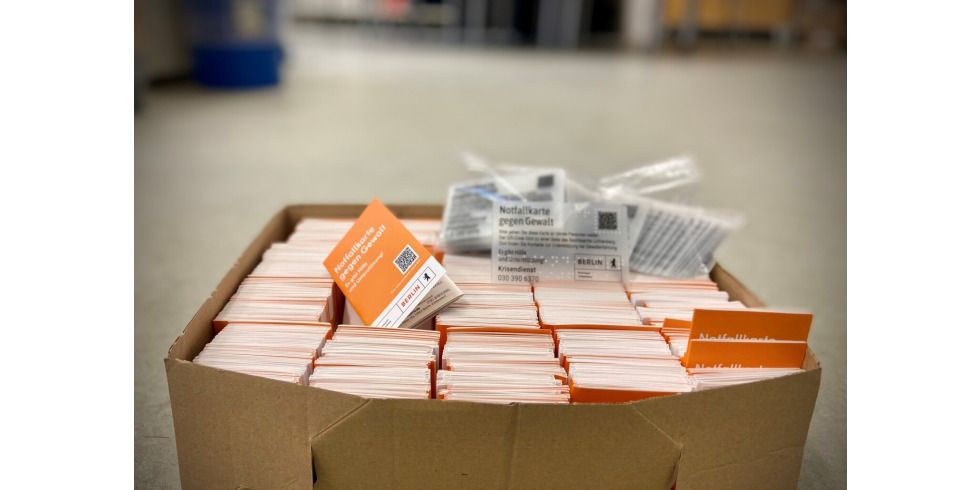 Karton mit Notfallkarten gegen Gewalt steht auf dem Boden. Im Karton liegen auch ein paar Karten mit Brailleschrift.