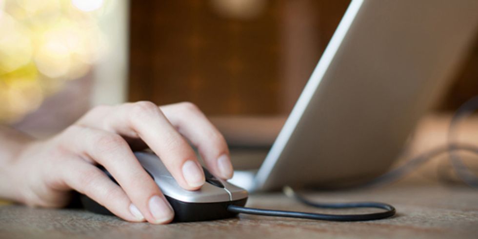 Hand auf der Maus neben einem Laptop
