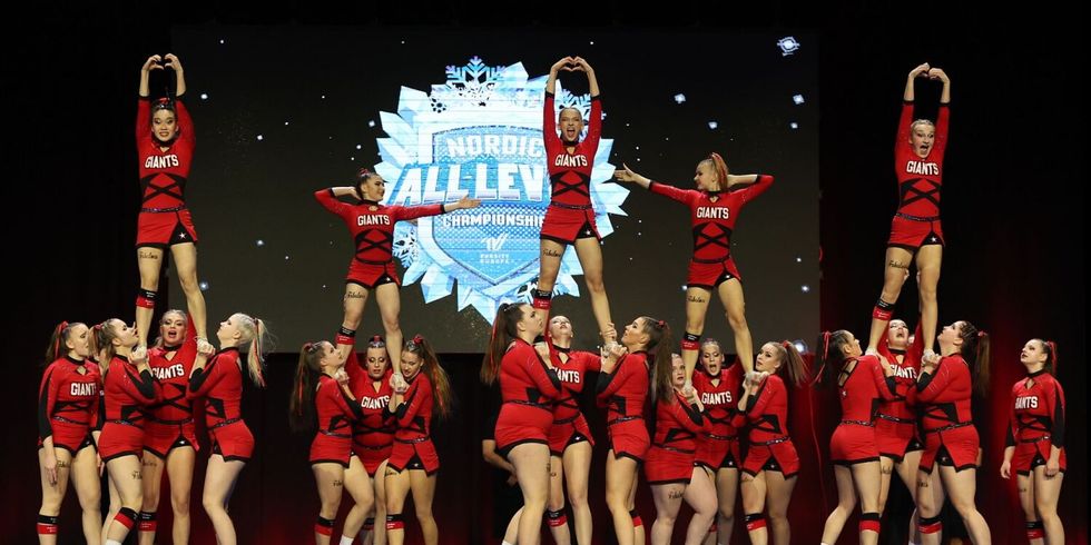 Fabulous Giants bei der Nordic All Level Championship - das Bild zeigt das Team, das vor dem Logo der Nordic Championship fünf Pyramiden aus Cheerleadern aufgebaut hat.