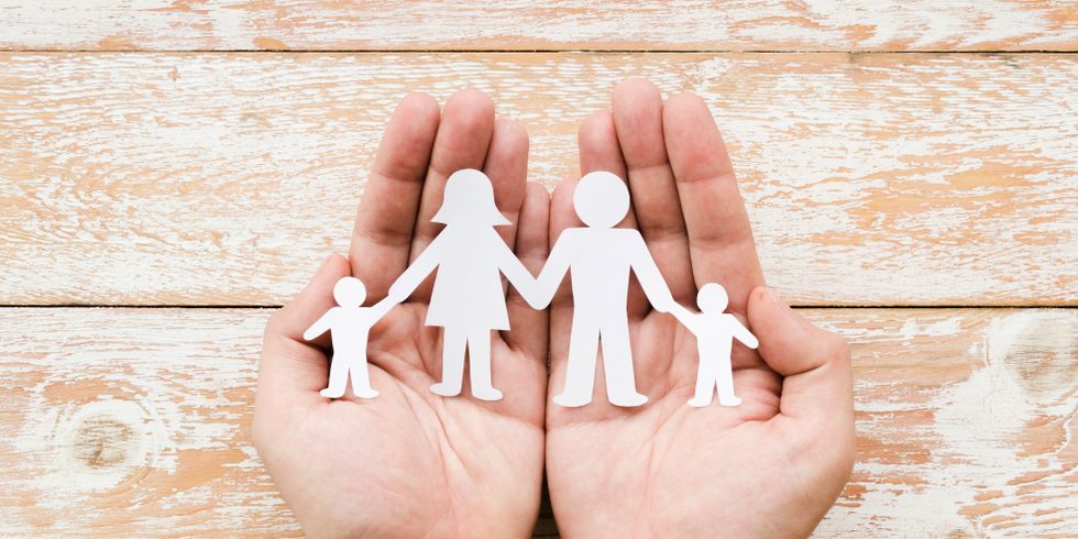 Hände die eine ausgeschnittene Papierfamilie halten