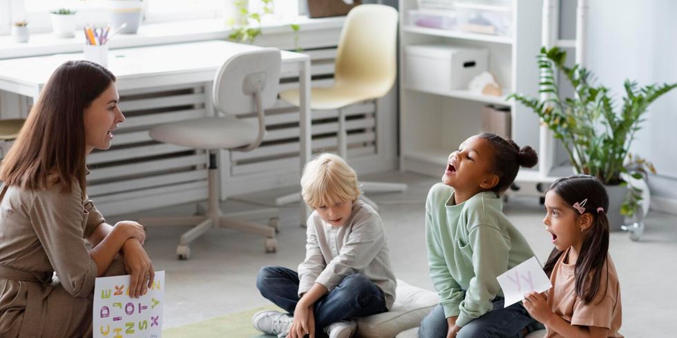 Frau betreut Kinder und lernt das Alphabet mit ihnen