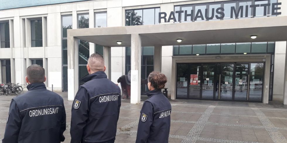 Drei AODs von hinten vor dem Bezirksamt Mitte von Berlin stehend.