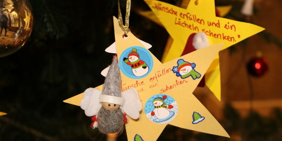 Kinder aus Pflege- und Betreuungseinrichtungen haben ihre Weihnachtswünswche in Sternform gebastelt und hängen diese jetzt an denNeuköllner Wunschbaum im Rathaus.
