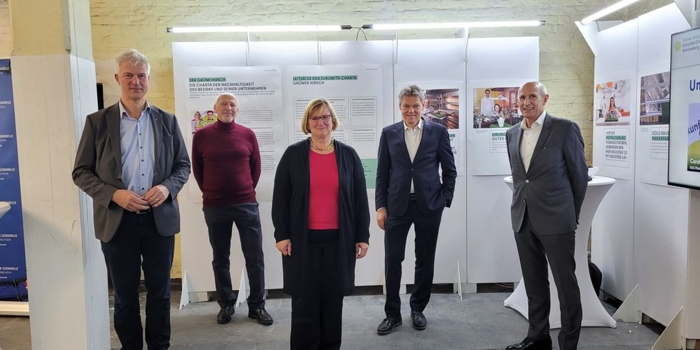 5 Menschen stehen in einer Hallo vor Aufstellwänden mit Plakaten.