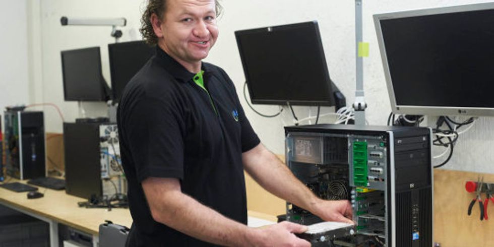 Mann an einem Tisch mit zerlegten Computern
