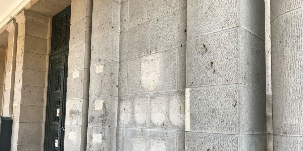 An der alten Steinwand neben einem Eingang zeigen leere Stellen, wo die Wappen auf der Rathausfassade vormals hingen.