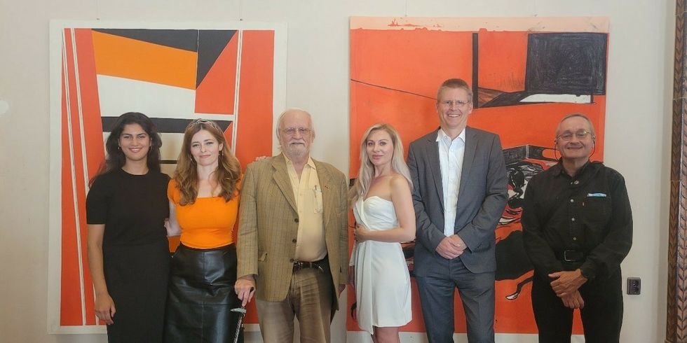 Mehrer Personen stehen vor zwei modernen Gemälden.