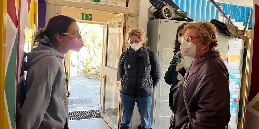 Vier Frauen stehen zusammen in einem bunten Eingangsbereich und reden miteinander.