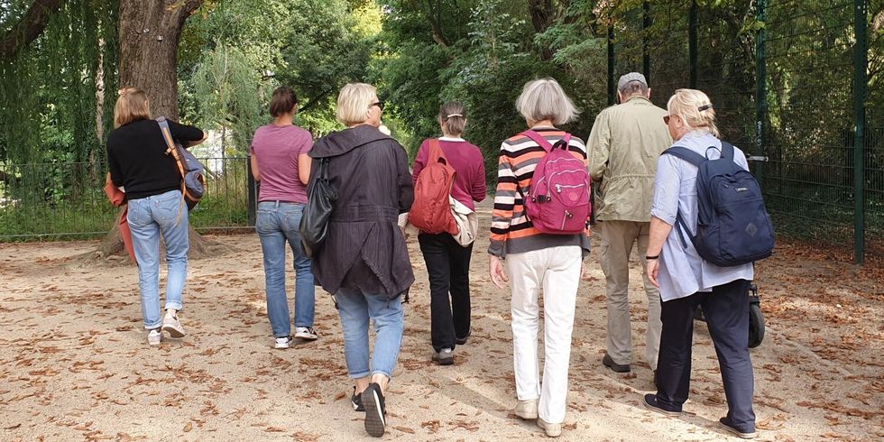 Sieben Personen laufen zusammen durch einen Park.