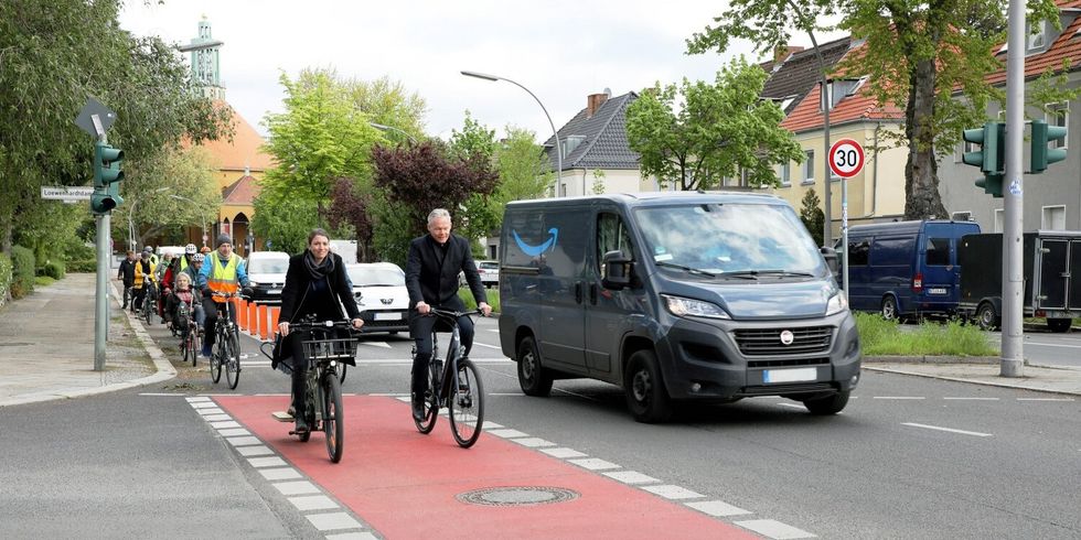 Eine Gruppe Menschen auf Fahrrädern fährt über eine Kreuzung mit markierten Fahrradstreifen.