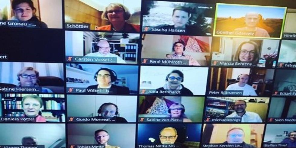 Bild eines Laptops auf dem Menschen zu sehen sind, die an einer Videokonferenz teilnehmen
