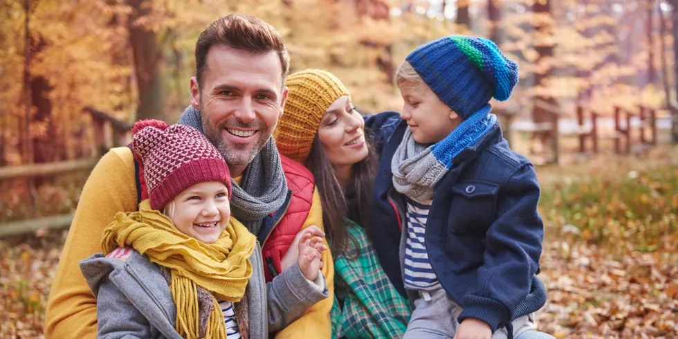 Eine vierköpfige fröhliche Familie im Herbstwald