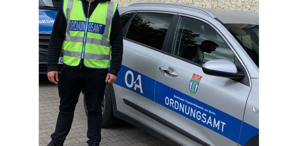 Ein Mitarbeiter des Ordnungsamts steht vor seinem Dienstfahrzeug