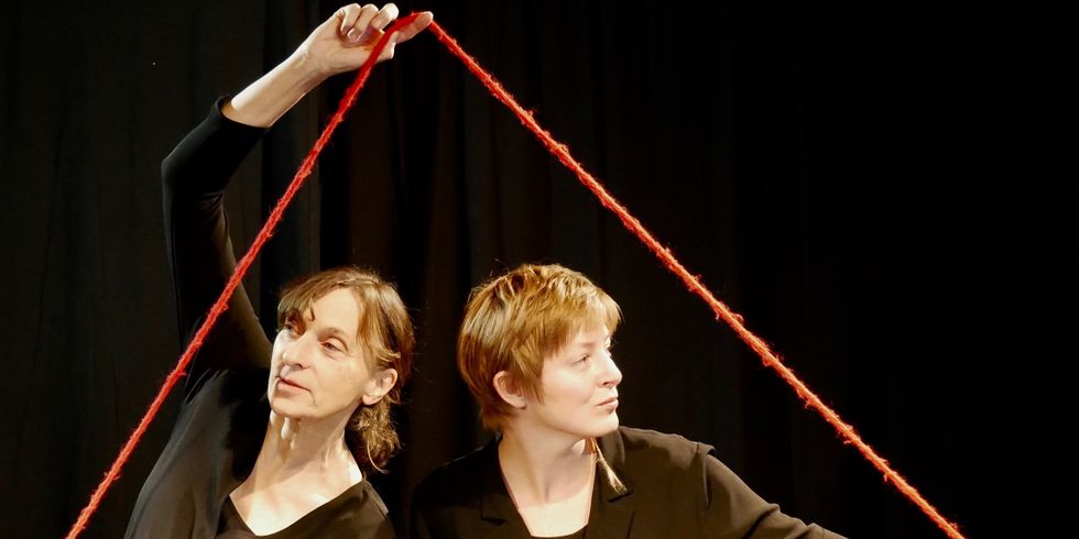 Zwei Frauen halten einen Fäden in Form eines Dreiecks