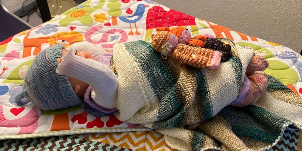Babypuppe trägt Strick aus den Kiezklubs