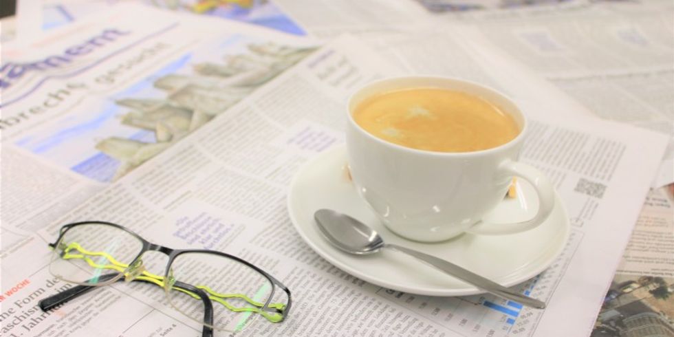 Abbildung einer Tasse, einer Brille und diverser Zeitungsblätter (hell)