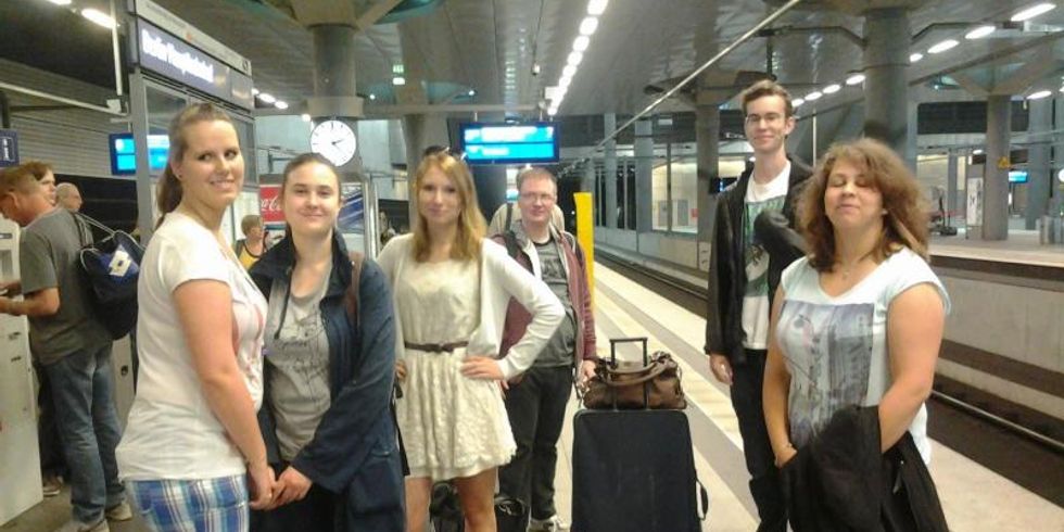Eine Gruppe Jugendlicher steht am Bahnhof und wartet auf den Zug