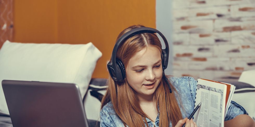 Kind mit Headset, Laptop und Buch