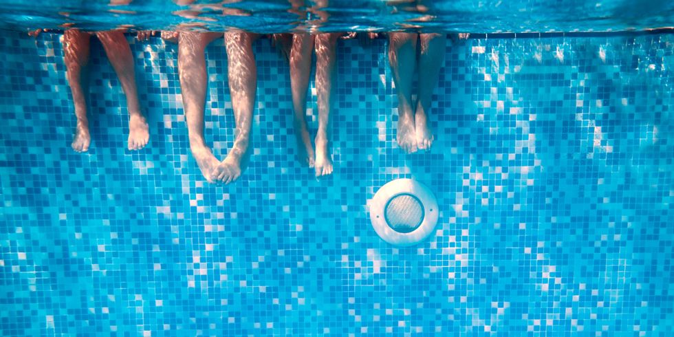 Beine von Kindern und Erwachsenen im Schwimmbad unter Wasser