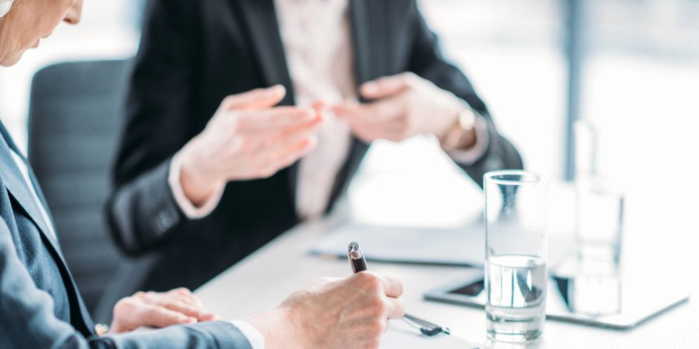 Zwei Frauen in Businesskleidung sitzen am Tisch und diskutieren
