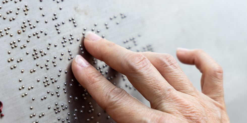 Hand fährt über Brailleschrift.