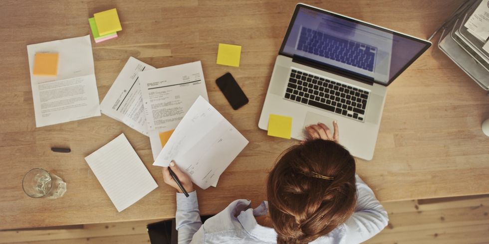 Frau arbeitend an ihrem Schreibtisch mit Dokumenten und Laptop