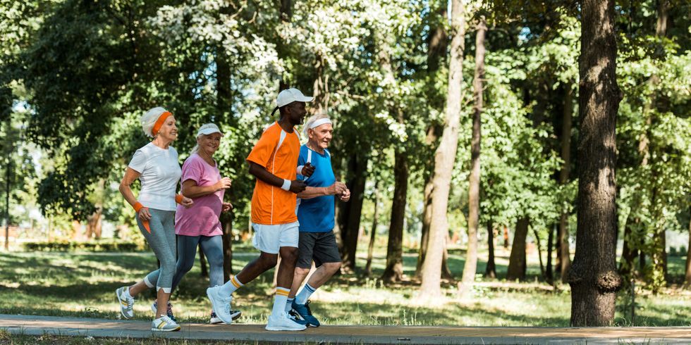 Fröhliche, multikulturelle und ältere Männer und Frauen, die im Park laufen