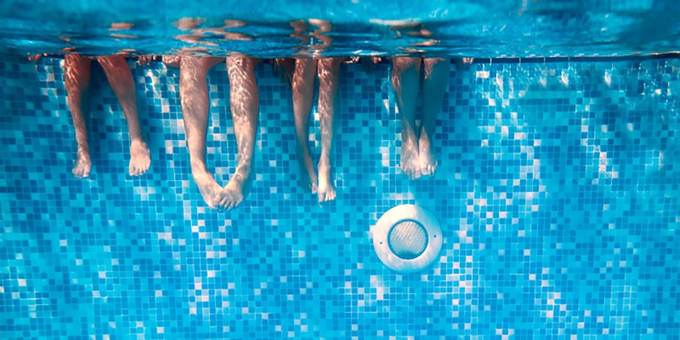 Beine von Kindern und Erwachsenen im Schwimmbad unter Wasser