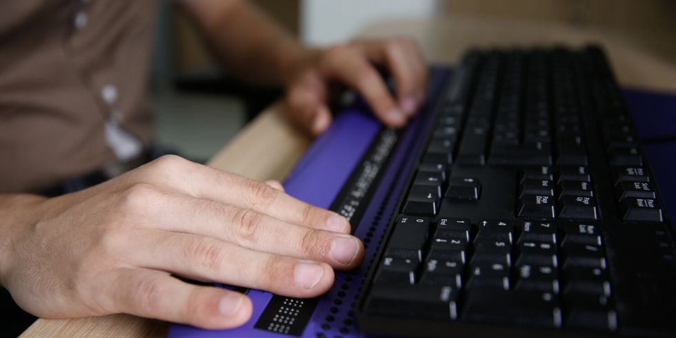 Person mit Händen an der Computertastatur mit Braillezeile