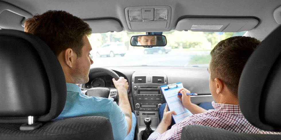 Fahrlehrer mit Klemmbrett und Fahrer