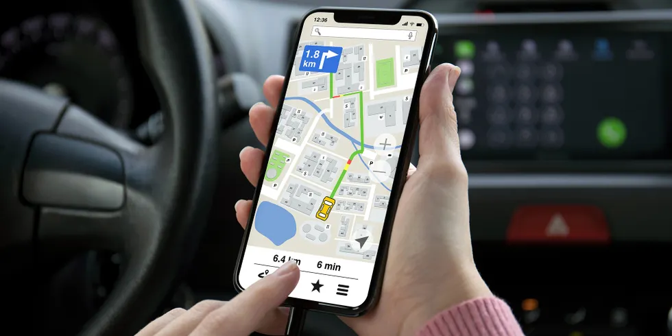 Eine Frauenhand hält ein Telefon mit einer App Navigationskarte auf dem Bildschirm