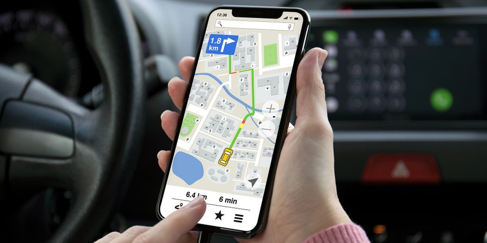 Eine Frauenhand hält ein Telefon mit einer App Navigationskarte auf dem Bildschirm