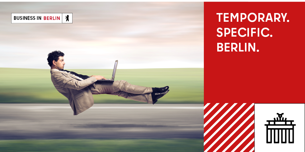 A man flies horizontally with a laptop (working across borders)