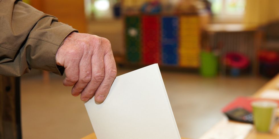 Stimmzettel wird in Wahlurne gesteckt