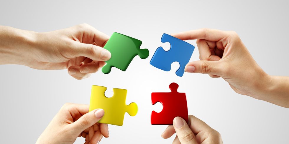 Hands and puzzle on gray background. Teamwork solving a puzzle