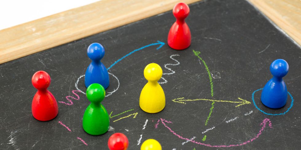 Spielfiguren auf einer Tafel verbunden mit Kreidelinien