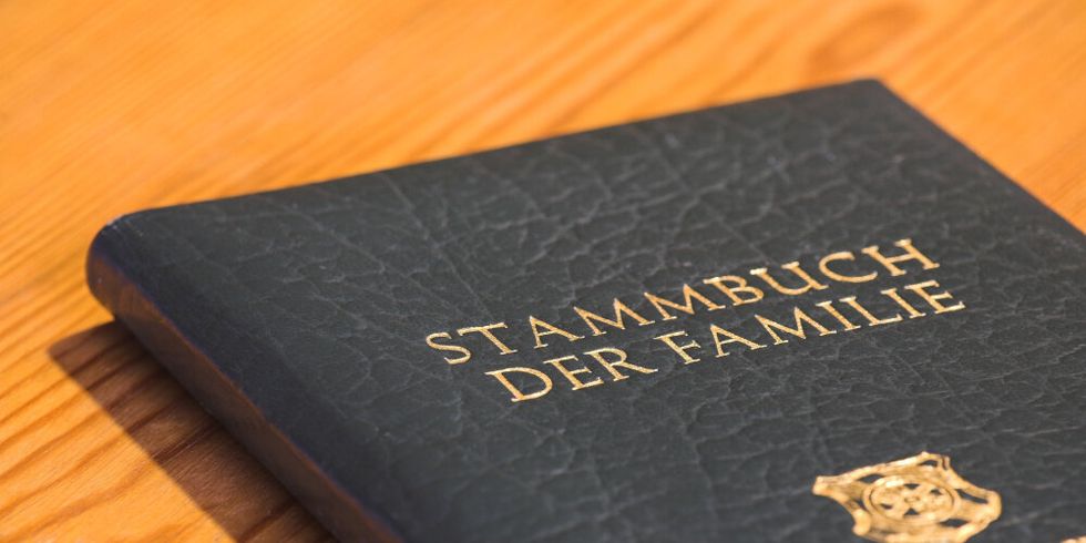 Ein Stammbuch aus schwarzem Leder liegt auf einem Holztisch