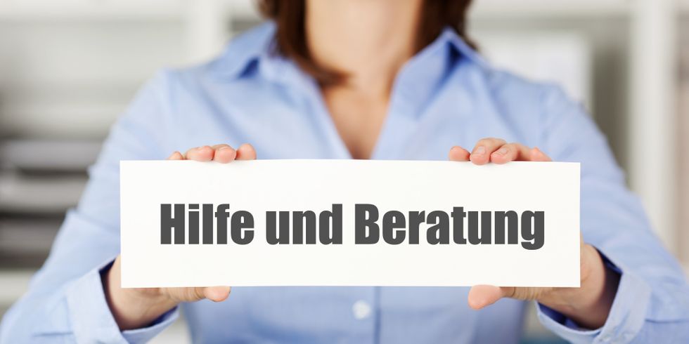 Eine Frau hält ein Schild mit der Aufschrift 'Hilfe und Beratung'