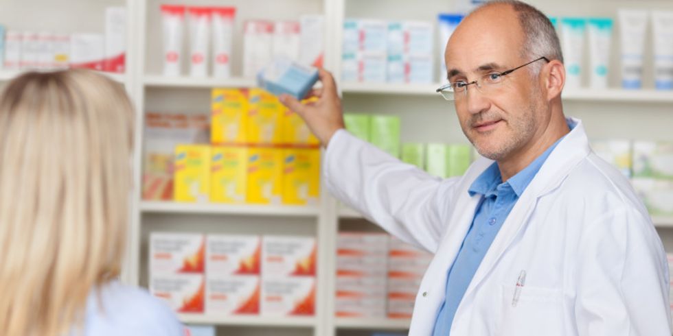 Apotheker greift nach einer Medikamentenpackung für eine Kundin