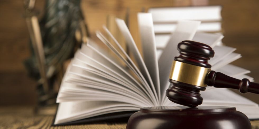Justitia, hölzener Richterhammer und ein aufgeschlagenes Buch