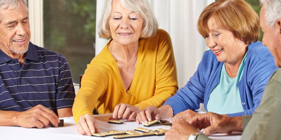 Zwei Seniorinnen und zwei Senioren spielen gemeinsam ein Brettspiel