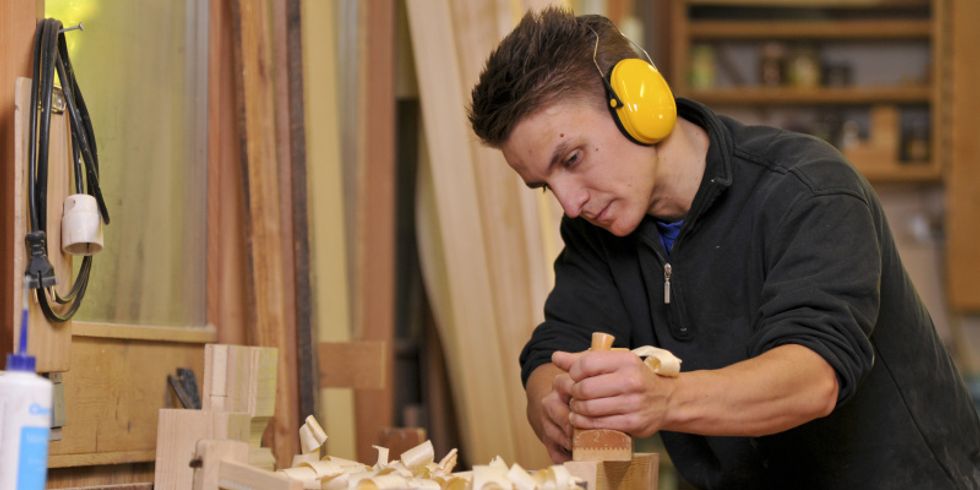 Jugendlicher der Holz hobelt