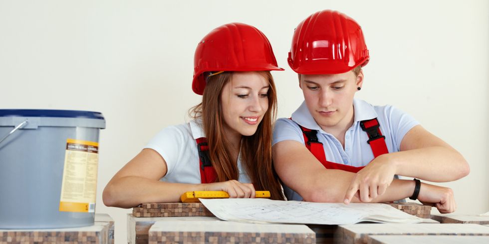 Junge Arbeiter mit Schutzhelm, die ein Haus planen