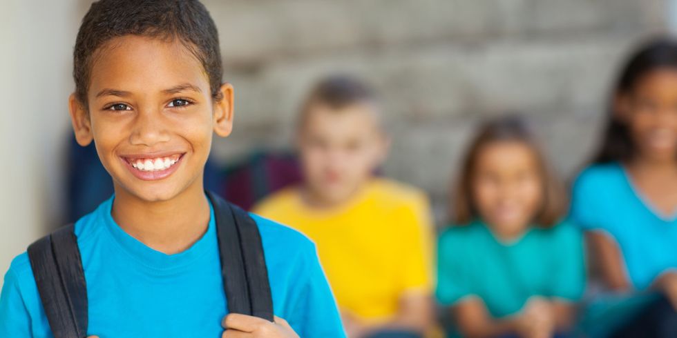 fröhlicher Junge im Vordergrund scharf und im Hintergrund 3 lachende Kinder unscharf fotografiert