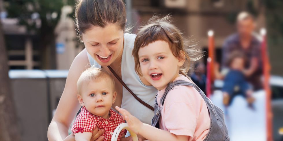 Mutter mit zwei Kindern auf dem Spielplatz