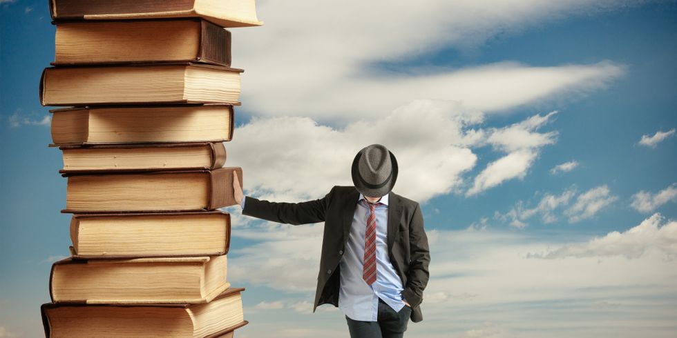 Ein Mann lehnt an einem großen Bücherstapel