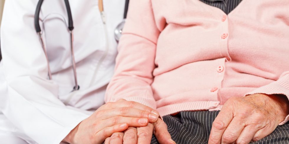 Medizinerin hält die Hand einer Seniorin