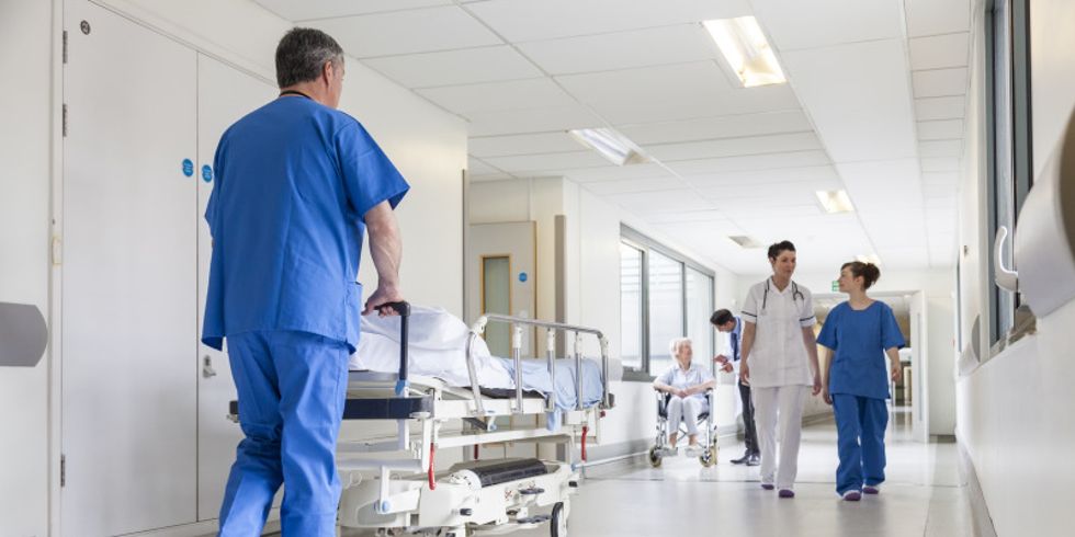 Mediziner schiebt Krankenbett durch Krankenhausflur