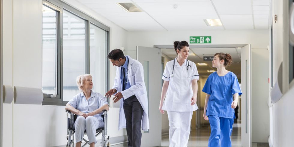 Krankenhausflur mit medizinischem Personal und Patientin im Rollstuhl