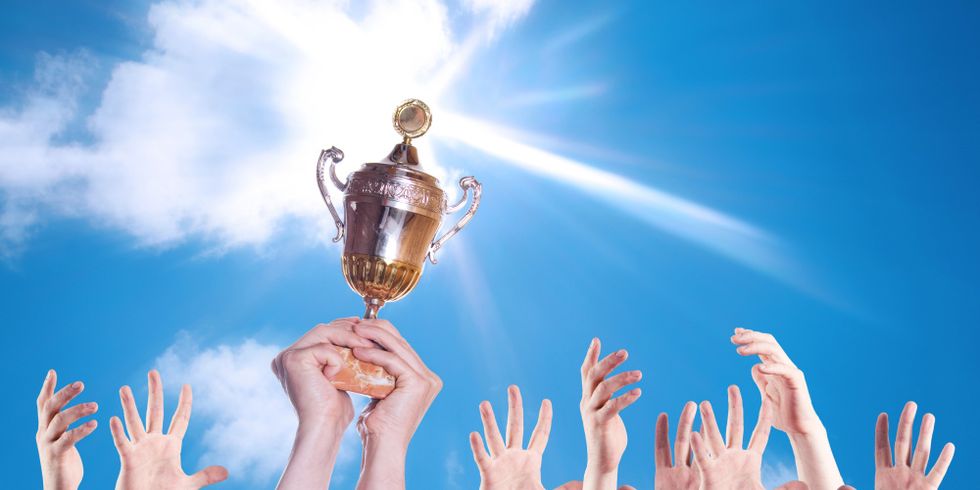 Hände mehrerer Personen mit einem Pokal